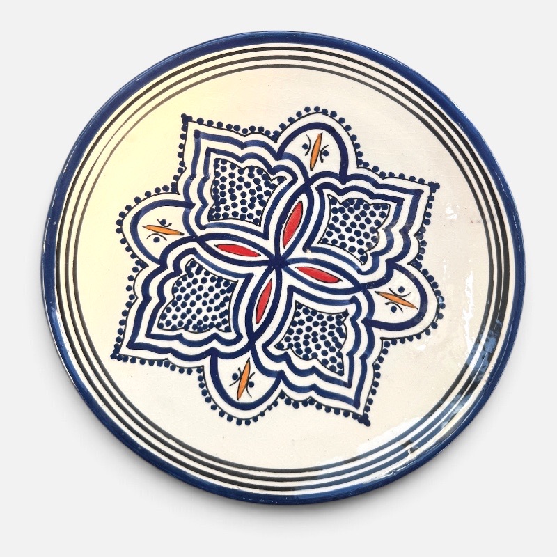 Assiette en céramique bleue ornée de motifs et de détails rouges et jaunes, fabriquée à la main au Maroc. Dimensions : 26 cm.