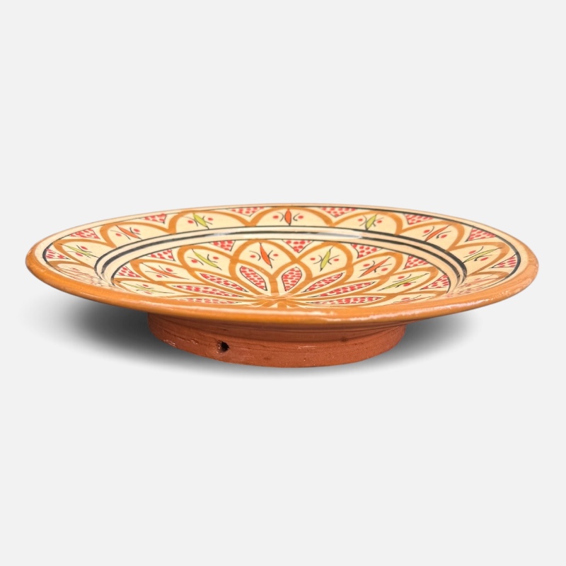Assiette en céramique ocre ornée de détails rouges et verts, fabriquée à la main au Maroc. Dimensions : 26 cm.