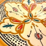 Assiette en céramique couleur ocre avec des détails couleur pétrole et orange, fabriquée à la main au Maroc, mesurant 26 cm.