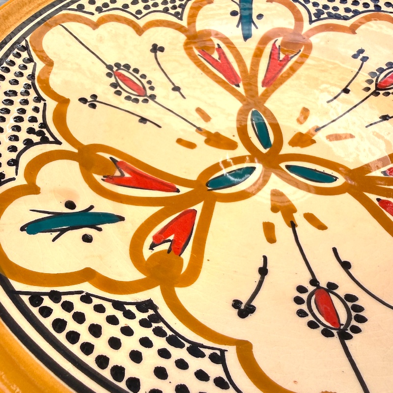 Assiette en céramique couleur ocre avec des détails couleur pétrole et orange, fabriquée à la main au Maroc, mesurant 26 cm.